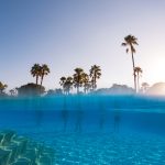 Underwater Photography Of People Standing In Pool With Copy Space. Beach Resort Vacation By Sea. Winter Or Summer Seaside Resort Holiday. Over Under Underwater Photography.