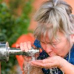 Woman Drinking Water From A Fountain Splashing In Her Face